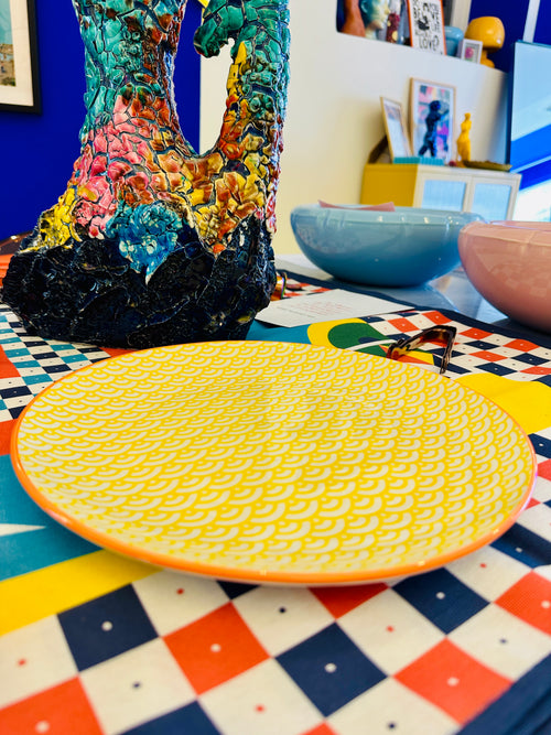 Assiette jaune et blanche à motif avec bordure orange.