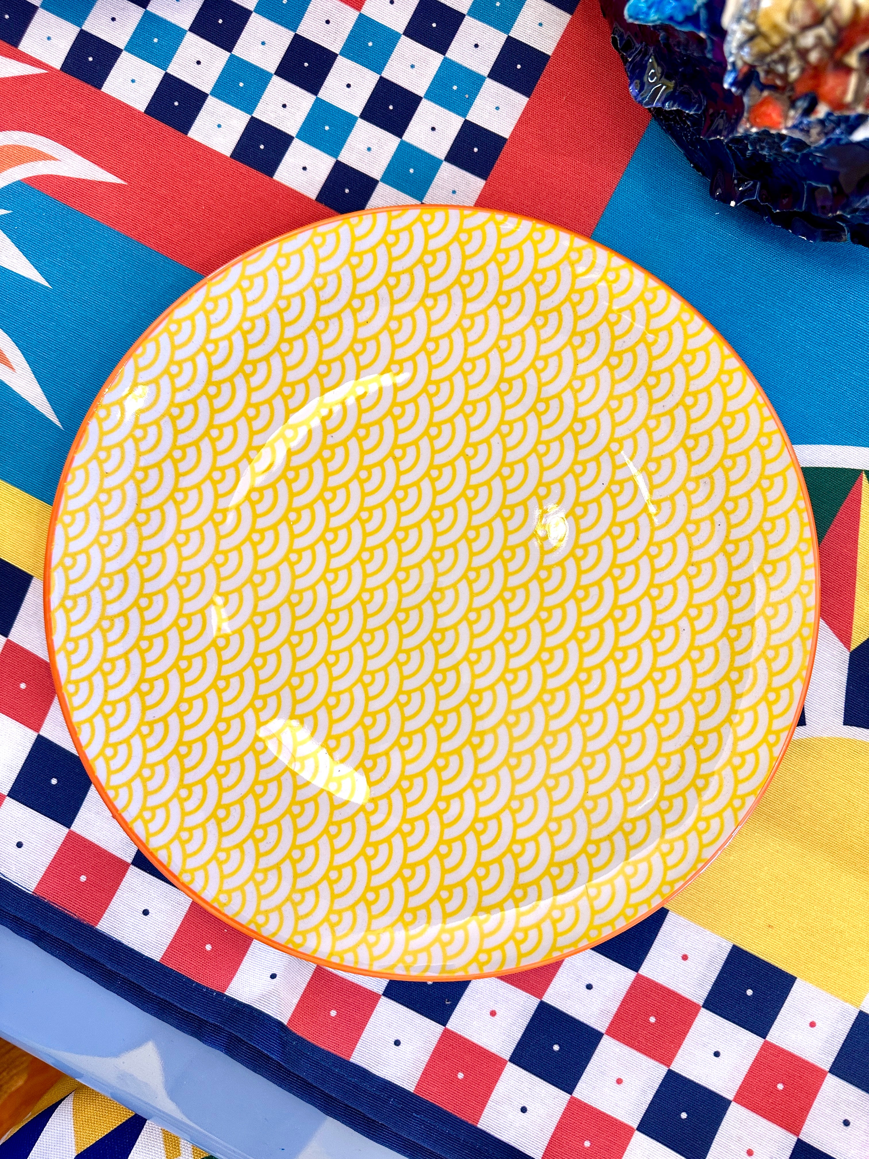 Assiette jaune et blanche à motif avec bordure orange.